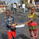 Somali children assist other civilians and security forces in their rescue efforts by carrying away unidentified charred human remains in a cardboard box, to clear the scene of Saturday's blast, in Mogadishu, Somalia.